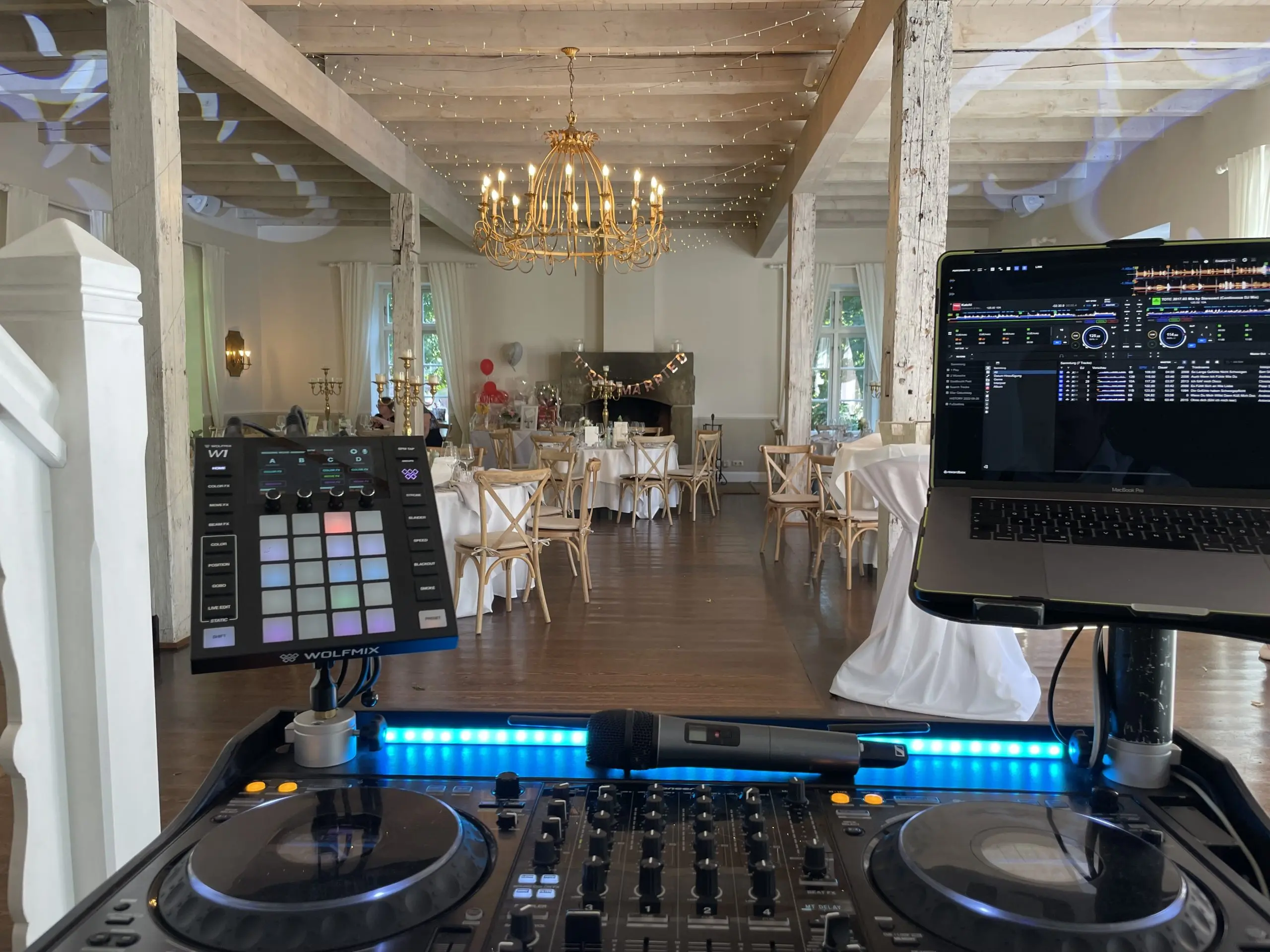 DJ-Setup bei einer Hochzeit auf Gut Pronstorf mit Blick in den festlich dekorierten Saal
